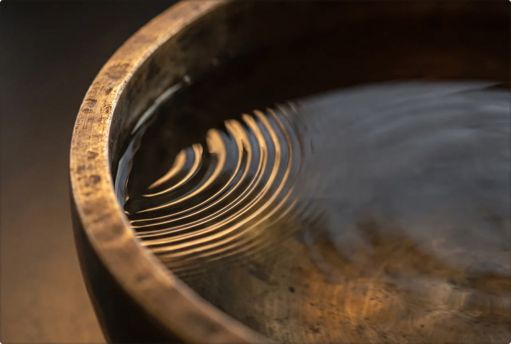 A struck bowl and ripples evoking sound and vibration